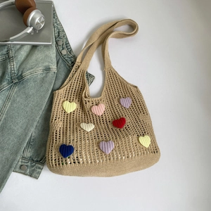 Close-up of khaki hollow knit tote bag featuring colorful knitted heart patches