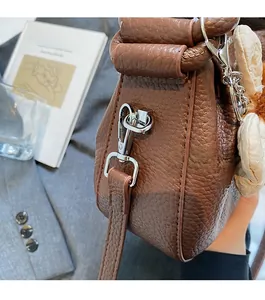 Detail of brown litchi pattern leather bag with silver metal hook and flower charm