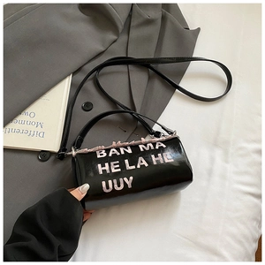 Détail du sac cylindrique noir avec lettrage rose et blanc et bandoulière amovible