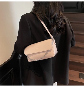 Detail of light pink baguette bag showing silver chain and leather strap on a model
