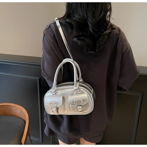 Silver metallic bucket bag with dual front pockets and metal buckles worn by model