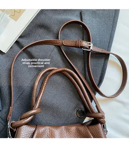 Detail of brown litchi pattern leather bag with adjustable strap and braided handles