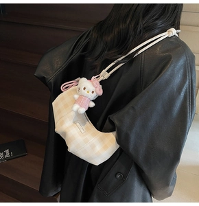 Detail of yellow checkered dumpling bag with a plush charm on black leather jacket