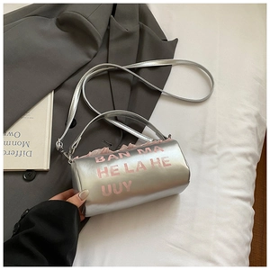 Détail du sac baril argenté métallisé avec texte rose et fine bandoulière longue