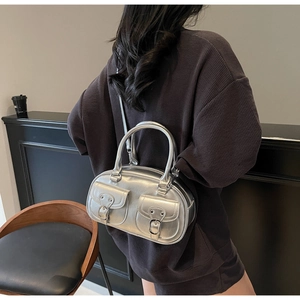 Silver retro bowling bag with front flap pockets shown as crossbody on shoulder
