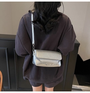 Detail of silver crossbody bag with metallic pleated texture and thick chain strap decoration
