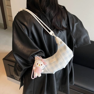 Detail of checkered dumpling bag with braided strap and cat plush on model back