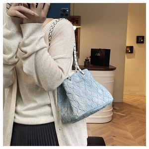 Macro shot of light blue quilted texture and silver chain strap on fashion tote bag