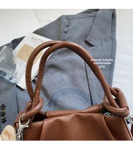 Detail of round leather handle on a brown pebble grain bag with silver metal hooks