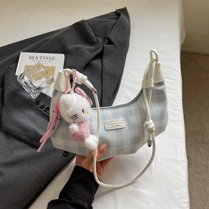 Detail view of blue gingham hobo bag with a cute cat plush charm and branded label