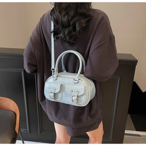 Detail view of light blue glossy handbag featuring utility pockets and silver metal buckles