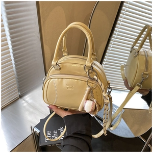 Detailed close-up of beige baseball-themed handbag with stitching and decorative pendant