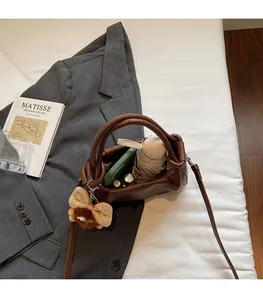 Interior view of brown leather crossbody bag holding a small umbrella and phone