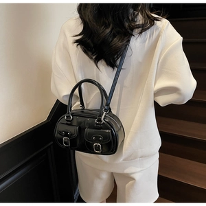 Detail of black patent leather bowling bag with silver hardware and front pockets