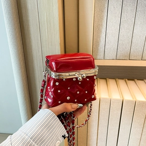 Detail of red quilted shiny leather mini bag with rhinestone studs and metal clasp