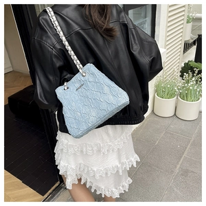 Detail of light blue pleated texture bag with silver chain strap and metal logo