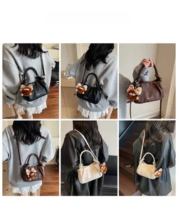 Model view showing small pleated crossbody bag in black brown and cream with plush charm