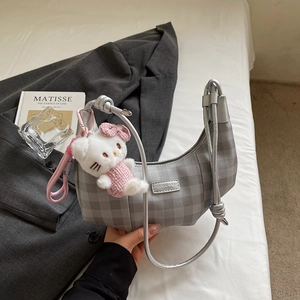 Detail of silver checkered hobo bag with kitten plush charm and brand leather label