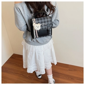 Detail of checkered mini backpack with bear charm and buckle on a model's back