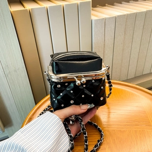 Detail of black quilted mini bag featuring silver studs and vintage metal clasp closure