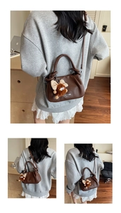Detailed side view of brown leather crossbody bag with logo and fuzzy monster charm