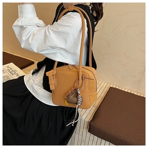 Detail of vintage brown box-shaped shoulder bag with white stitching and heart charm