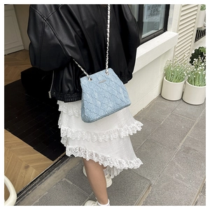 Outdoor shot showing the silver chain and ruched texture of the light blue handbag
