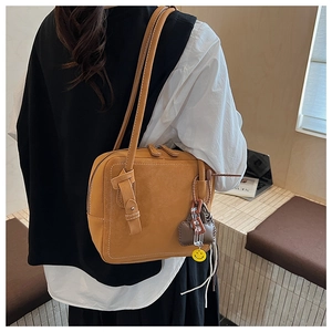 Detail of yellow leather tote bag with smile face charm and acrylic chain accents