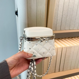 Close-up of white quilted mini square bag with rhinestone accents and silver chain strap