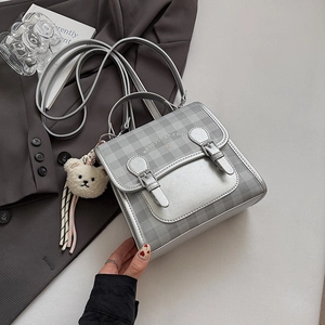 Detailed view of silver plaid backpack with ribbon bow and cute white bear keychain