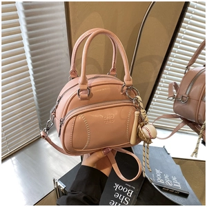 Detail of pink shell bag with baseball stitching, brand embossing and bag charms