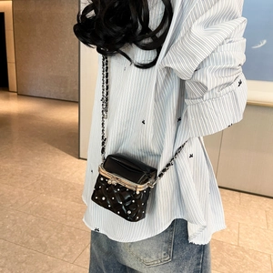 Model trägt gesteppte schwarze Ledertasche mit Perlen und Metallkettenriemen im Detail