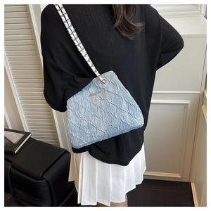 Detail of light blue crossbody bag with pleated texture and silver chain strap