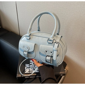 Detail of light blue faux leather handbag featuring silver buckles and front pockets