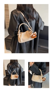 Detail of beige pleated shoulder bag with lychee texture and cute brown plush charm