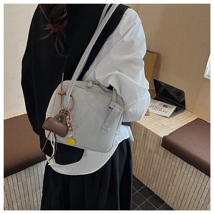 Detail of grey PU leather tote bag featuring a cute smile pendant and mini bag charm