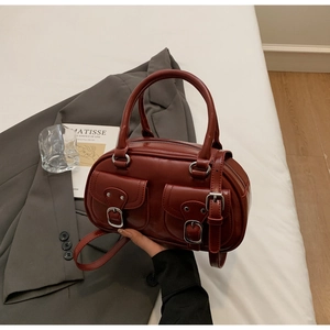 Detail view of burgundy leather shoulder bag with vintage metal buckles and front pockets