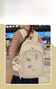 Detail view of cream white canvas backpack featuring transparent PVC ita-bag pocket with plush charm