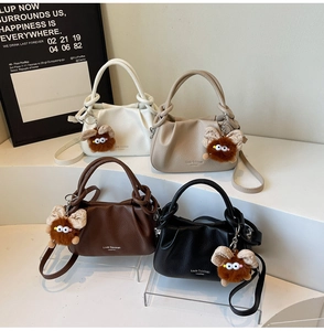 Detail of four pleated faux leather crossbody bags in cream, beige, brown, and black colors