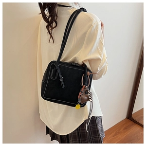 Detail of minimalist black tote with white contrast stitching and decorative charms