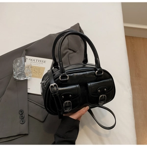 Close-up of black glossy leather bag with dual front pockets and silver buckles