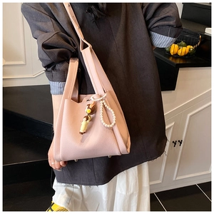 Borsa a secchiello in pelle rosa con ciondoli di perle e orsetto indossata da modella