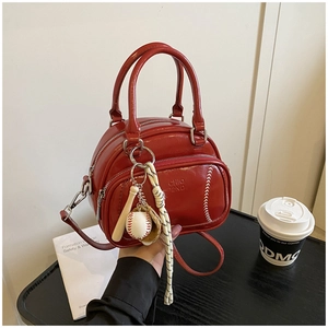 Detail of red pillow handbag with baseball stitching and miniature sports charms