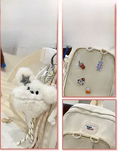 Detail view of cream school backpack with plush animal pendant and decorative badges