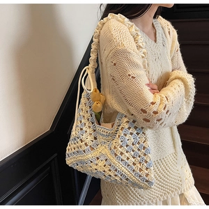 Detail of handmade knit tote bag with yellow tulip charm and woven shoulder strap texture