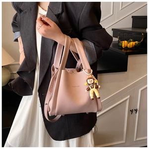 Borsa a secchiello rosa con trama litchi e ciondolo a forma di bambola e perla moda