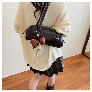 Détail du sac baguette en cuir café avec breloque nœud et détails de perles