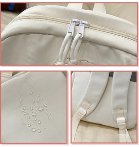 Detail view of cream nylon backpack featuring water-resistant fabric and dual-zipper closure