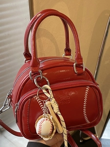 Red patent leather pillow handbag with baseball stitching and themed keychain