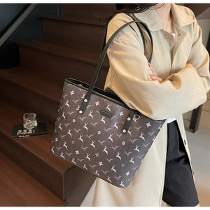Detail of printed tote bag with white reindeer patterns and black leather handles